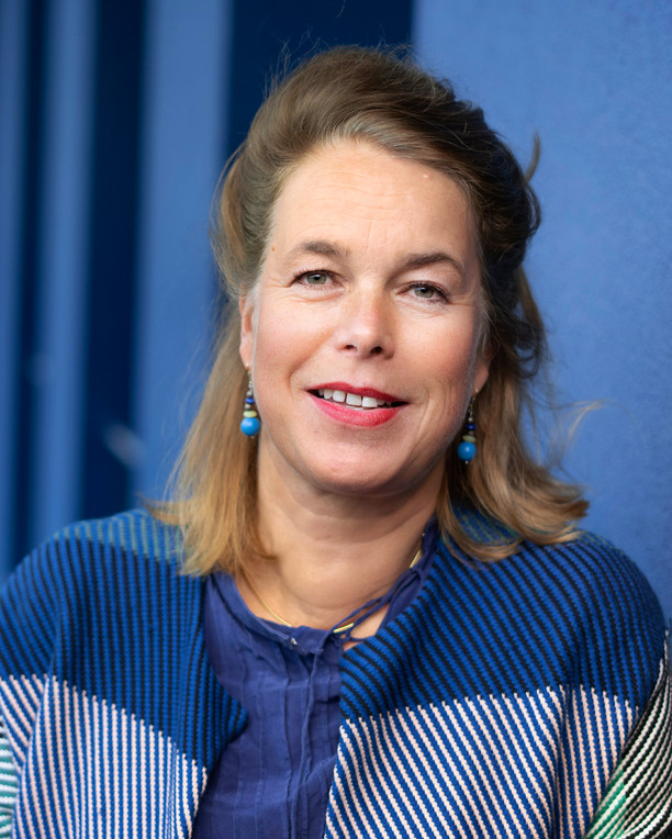 Eine Frau mit blondem Haar vor einer blauen Tür.